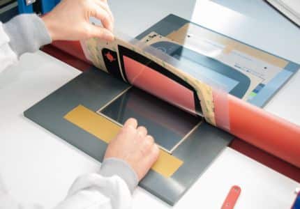 "Hand mit Daumen hochgestreckt, im Hintergrund Automobildesign. Finger zeigen auf Schriftart mit Nagel. Materialeigenschaften und Technik werden dargestellt. Symbol für Veröffentlichung."