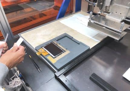 Mitarbeiterin richtet Touchscreen für Optical Bonding ein