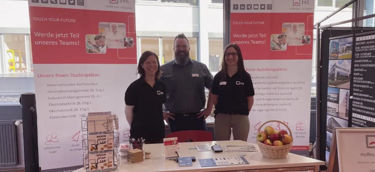 drei Mitarbeiter von H+K stehen am eigenen Stand auf der Ausbildungsmesse