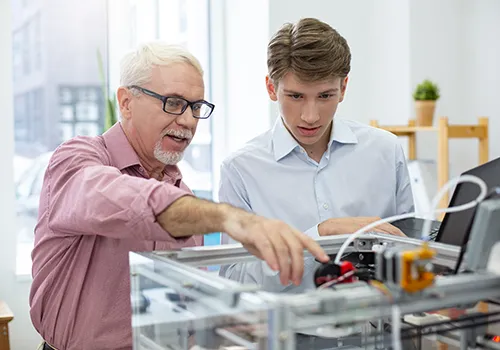 Mitarbeiter erklärt Praktikant Maschine