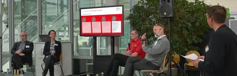 Vier Personen sitzen auf einer Bühne und diskutieren